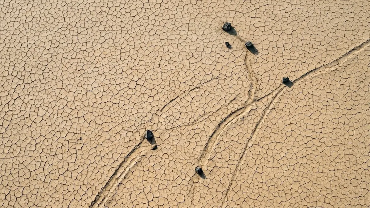 Aerial drone view of Racetrack Playa showing curved parallel trails across cracked mud